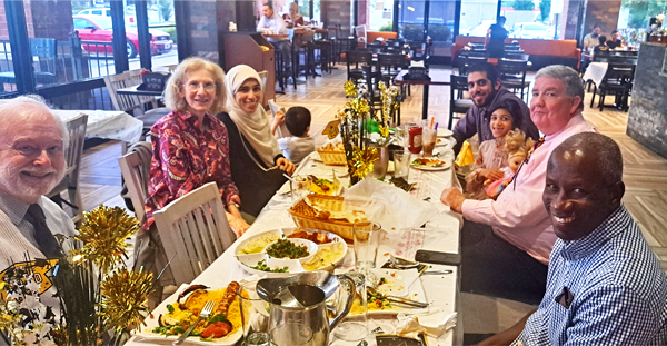 Fellow, their family, and a faculty members sitting at a table in a restaurant