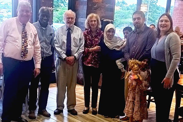 Fellow, their family, and a faculty members standing before an inside window