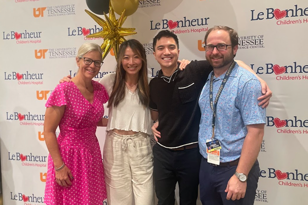 Faculty and fellows in front of a Le Bonheur banner