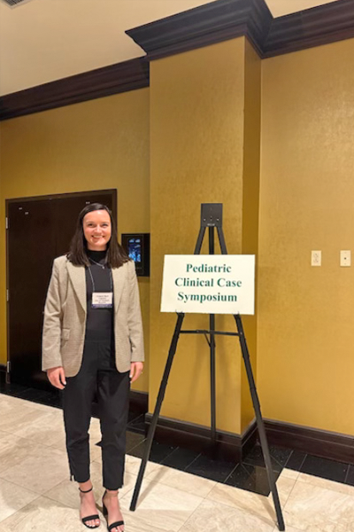 Resident standing before a symposium sign