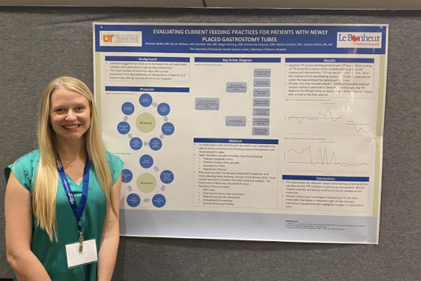 Resident standing before a poster presentation