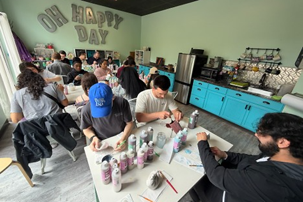 Residents seated at tables in a craft studio working on painting projects