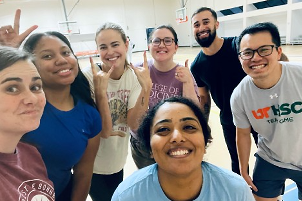 Seven residents posing on an indoor basketball court during a casual team‑building activity.