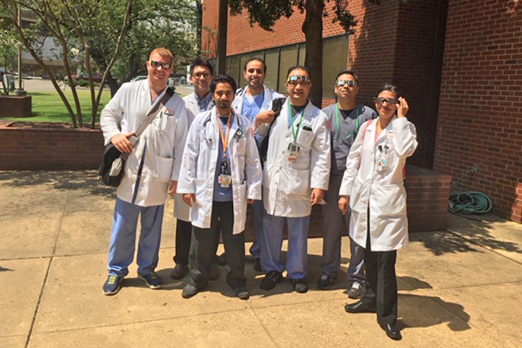 Fellows ouside in white coats and sunglasses