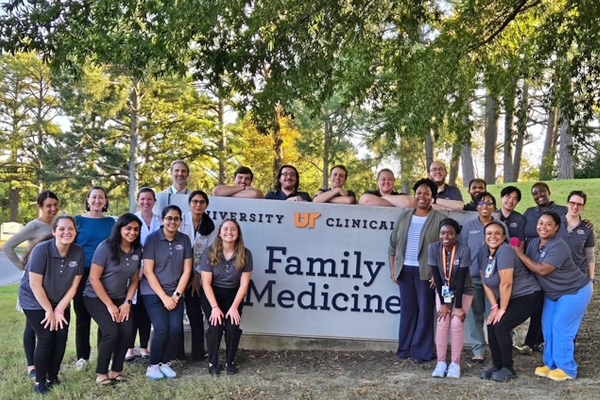 Residents outdoors in front of a UT Family Medicine sign