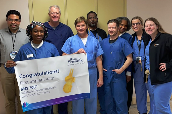 Residents and faculty holding a first implant with AMS 700 banner